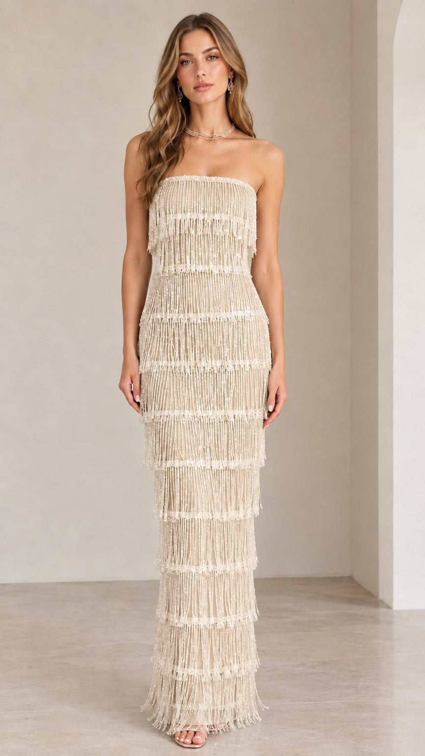 Front view of model wearing champagne strapless tiered beaded fringe maxi dress