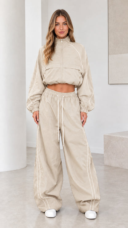 Front view of model wearing beige cropped windbreaker and parachute pants set