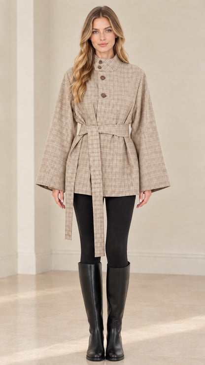 Front view of woman wearing beige plaid belted cape jacket