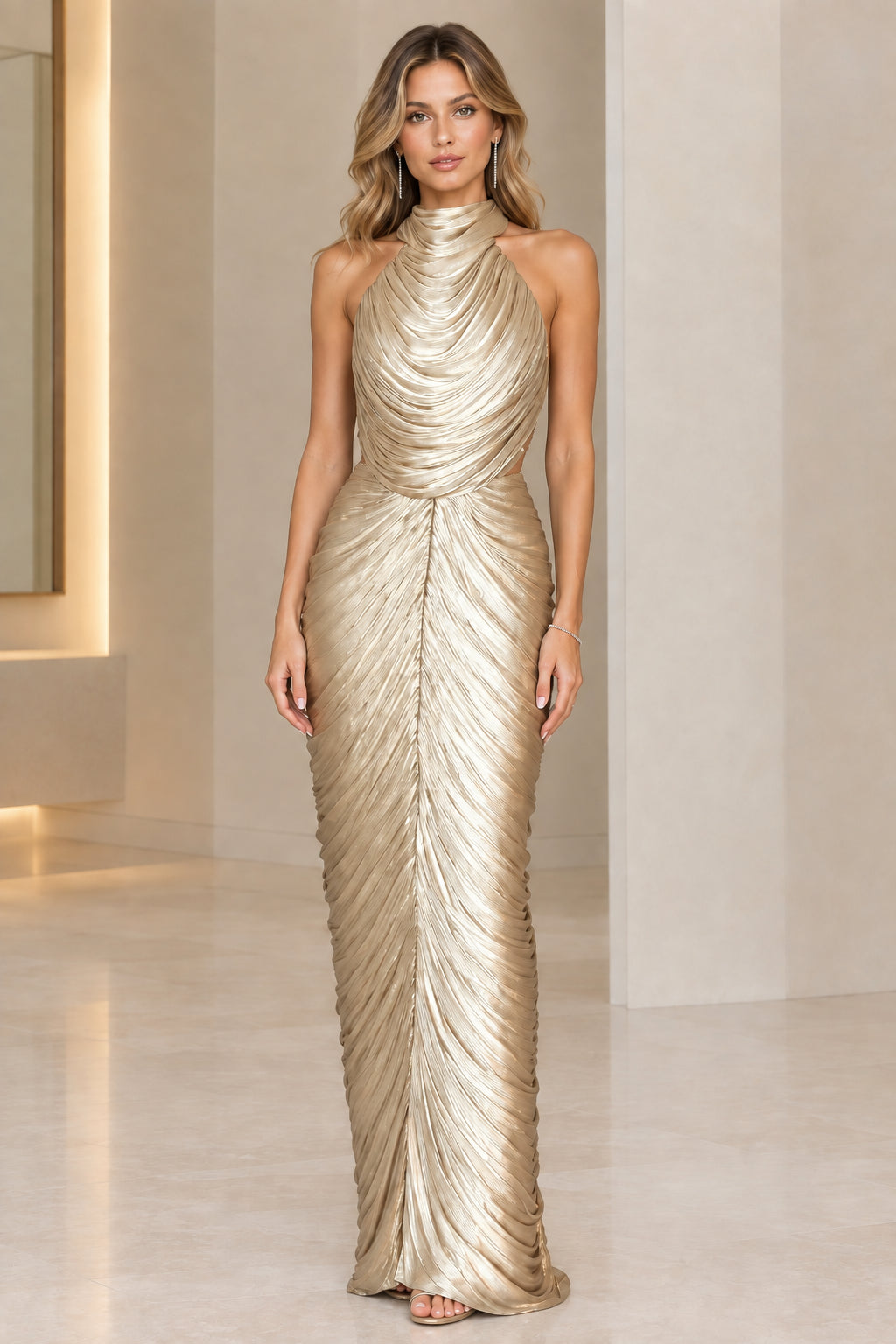 Model wearing champagne gold metallic pleated floor-length halter gown