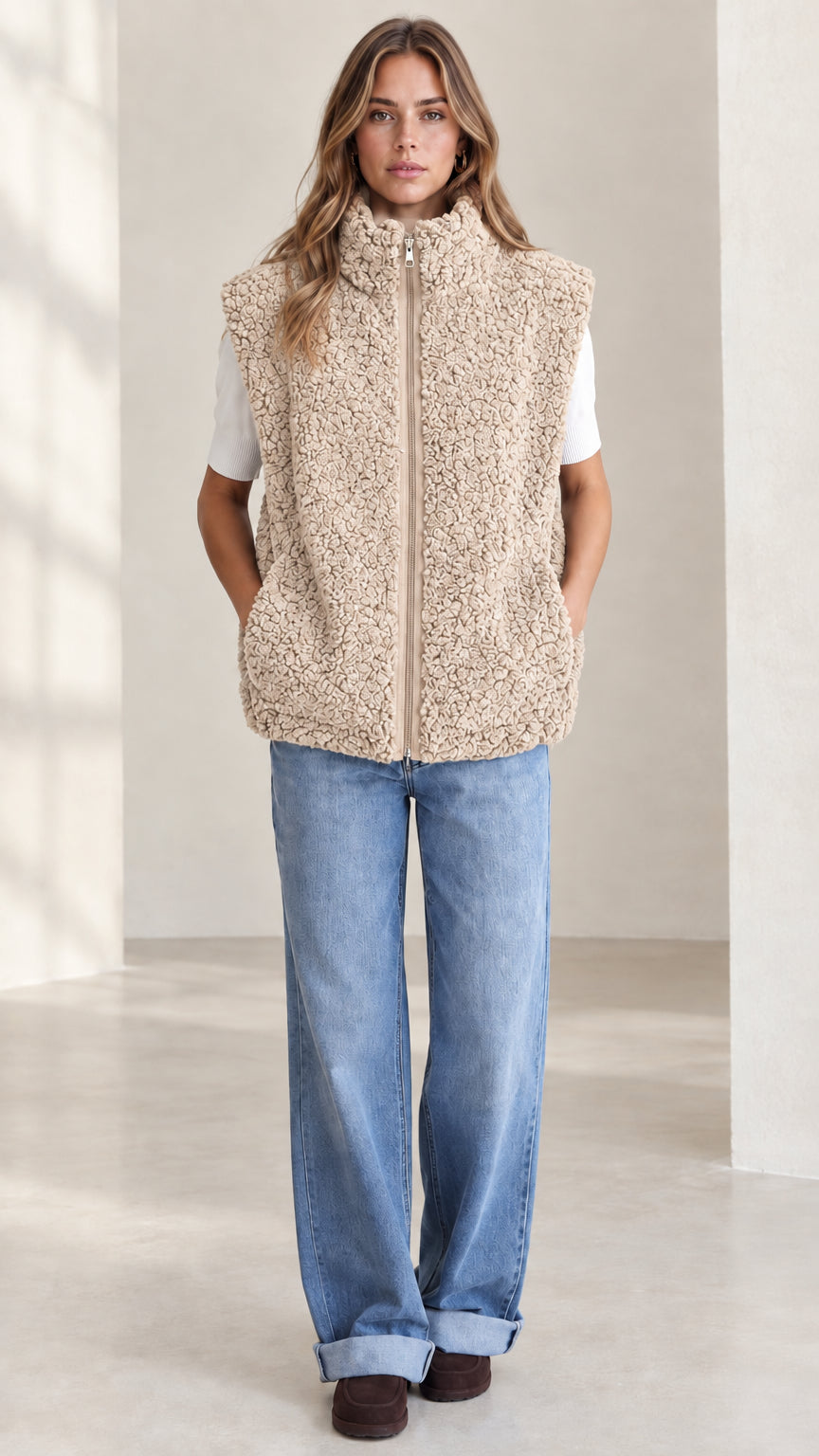 Front view of woman wearing beige sherpa fleece zip-up vest
