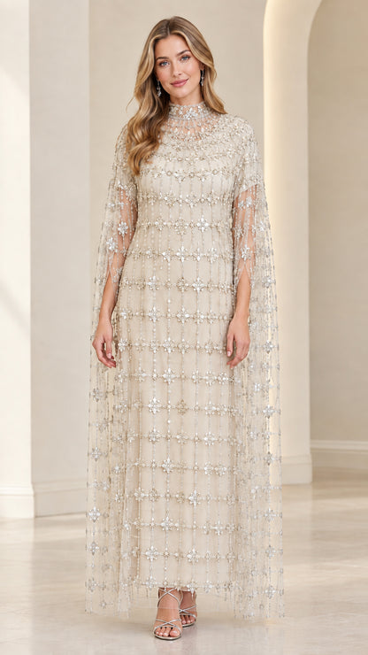 Front view of model in Champagne beige embellished evening gown with sheer cape